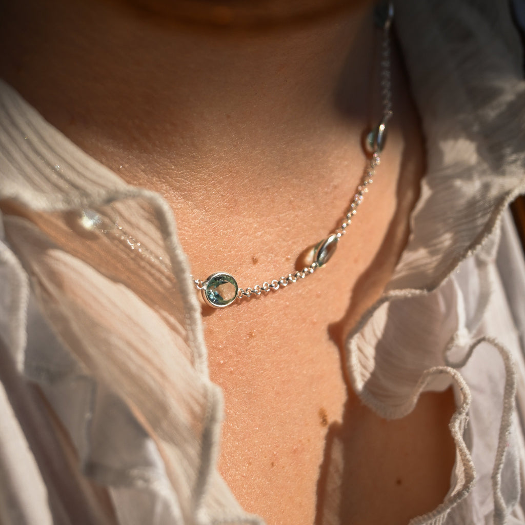 Close-up of a necklace on a person wearing a light-colored shirt.