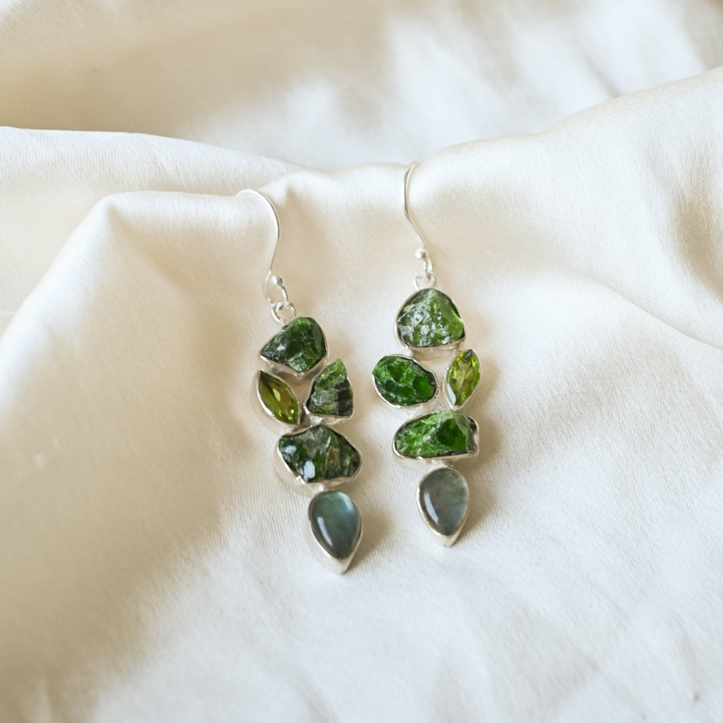 Green stone earrings on a white fabric background