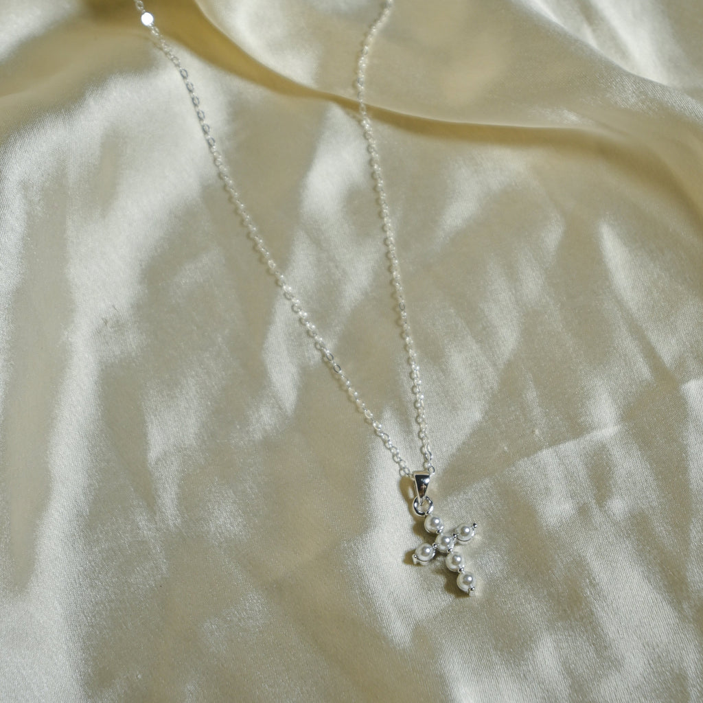 Silver necklace with a delicate pendant on a light fabric background