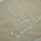 Silver necklace with a simple ring pendant on a beige fabric background