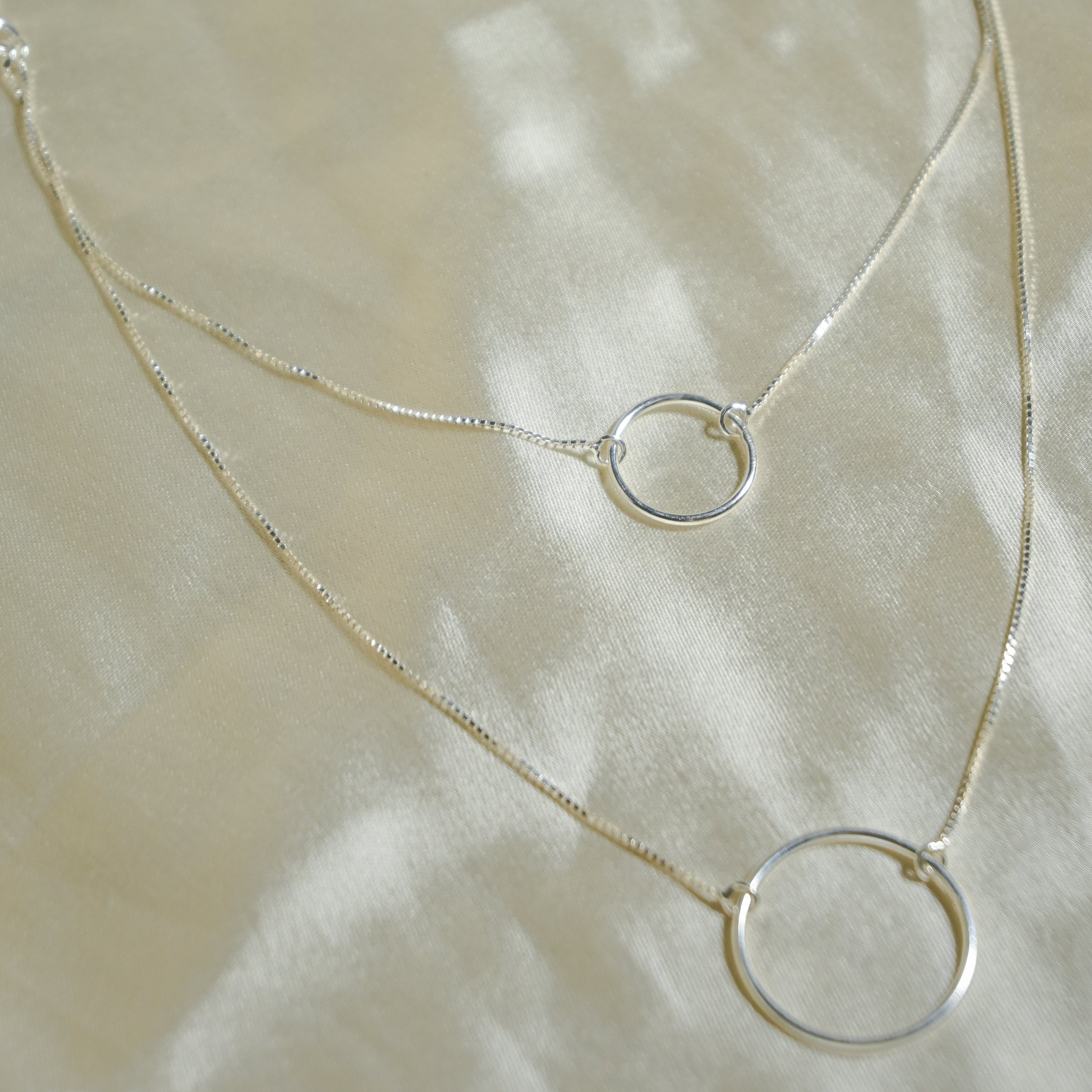 Silver necklace with circular pendants on a light fabric background