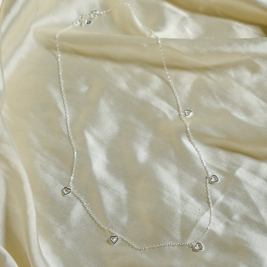 Delicate silver necklace on a beige fabric background