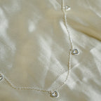 Silver heart-shaped necklace on a beige fabric background