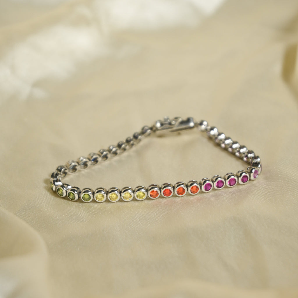 Silver bracelet with colorful beads on a beige fabric background
