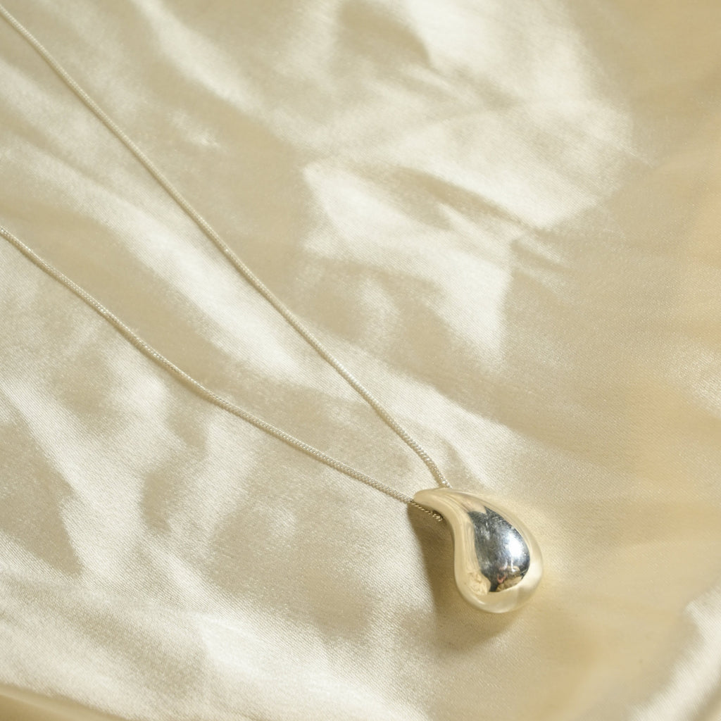 Gold necklace with a pendant on a beige fabric background