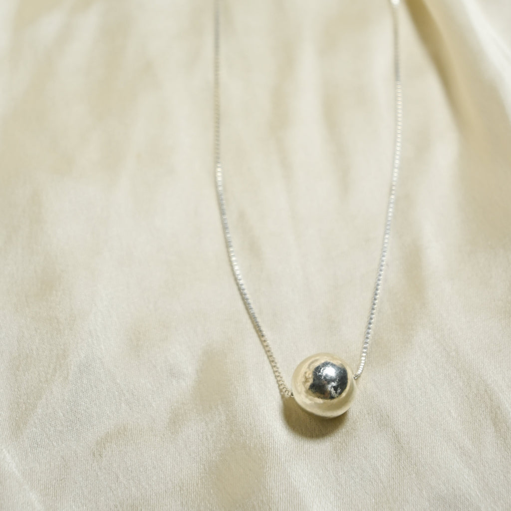 Necklace with a round pendant on a beige fabric background
