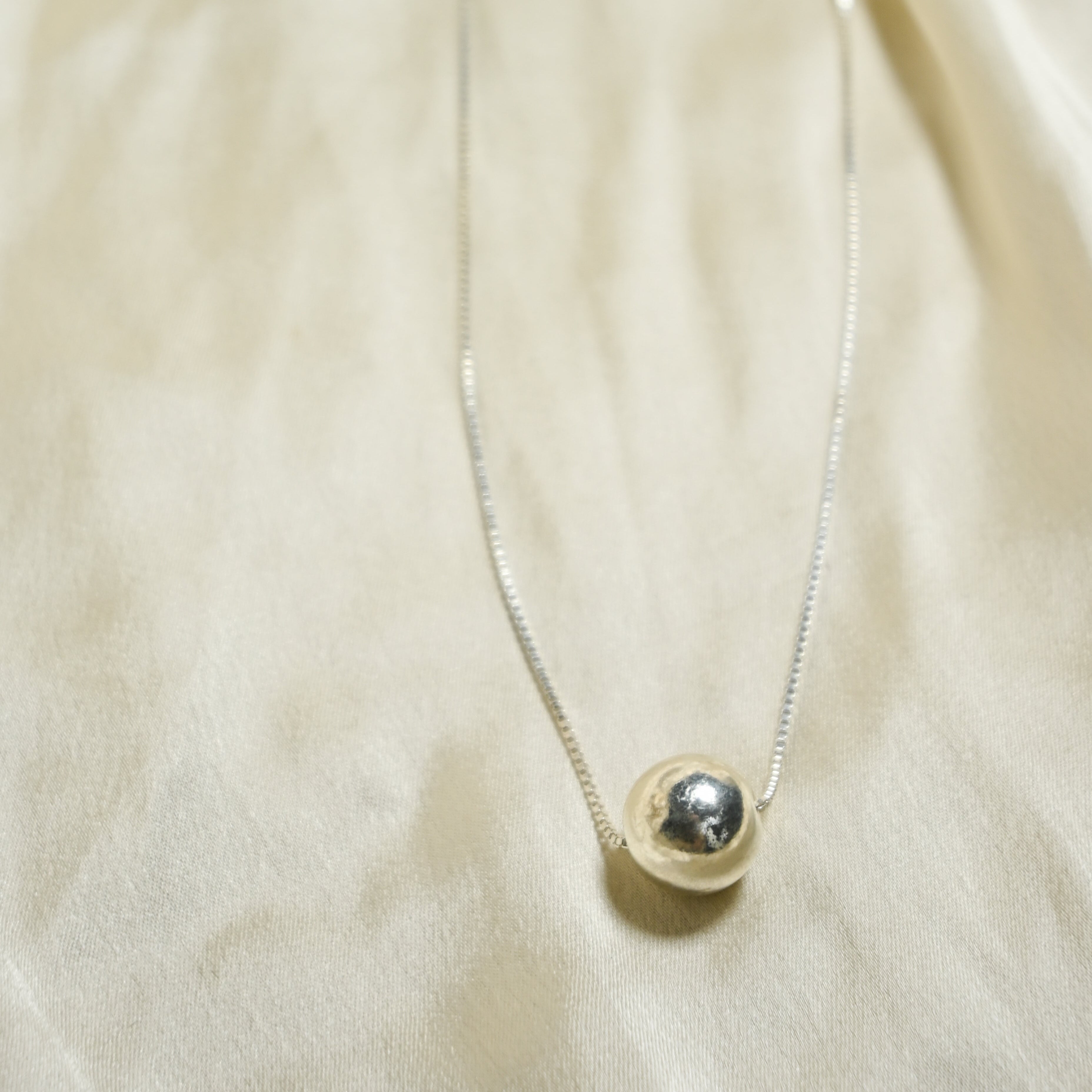 Necklace with a round pendant on a beige fabric background