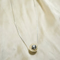 Necklace with a round pendant on a beige fabric background