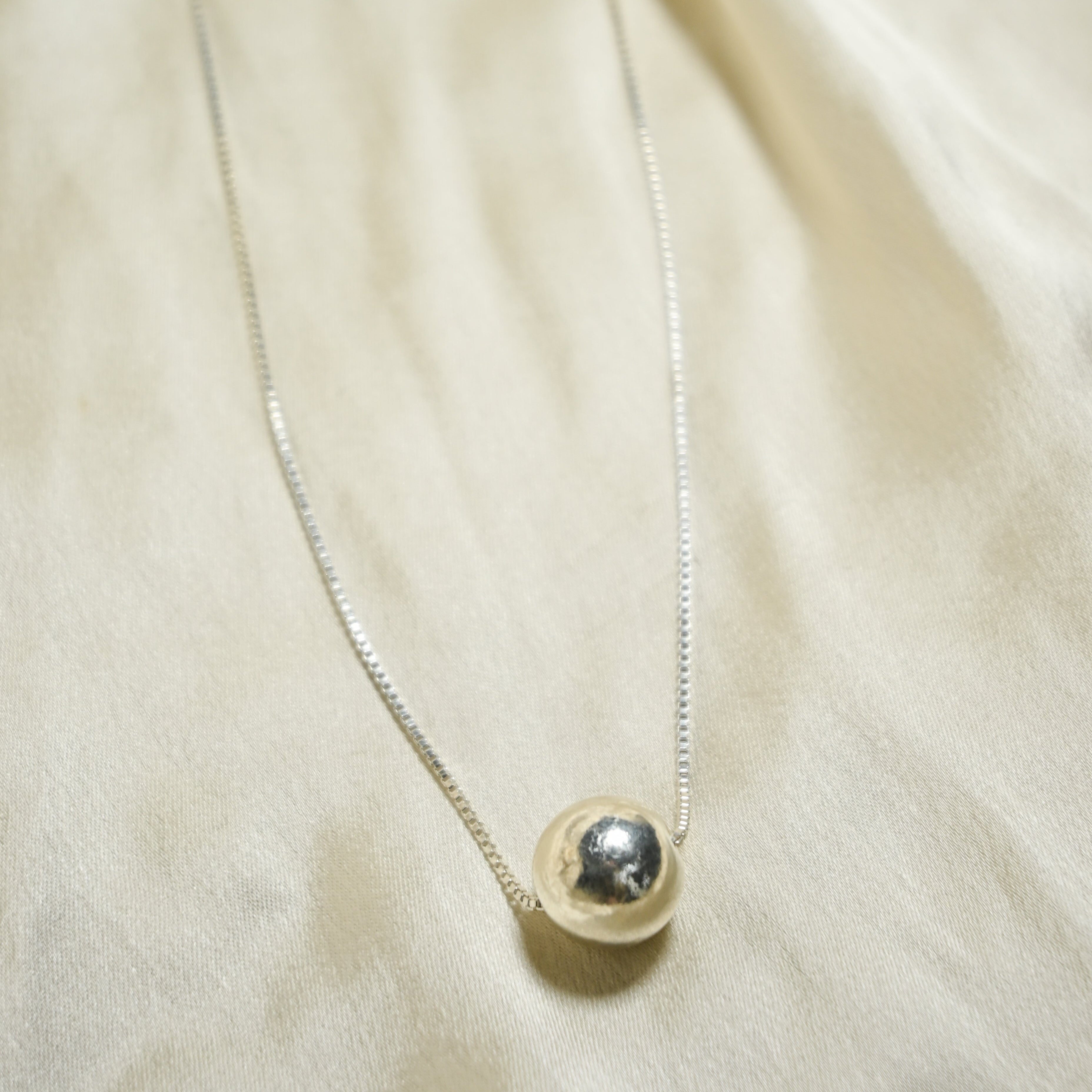 Necklace with a round pendant on a beige fabric background