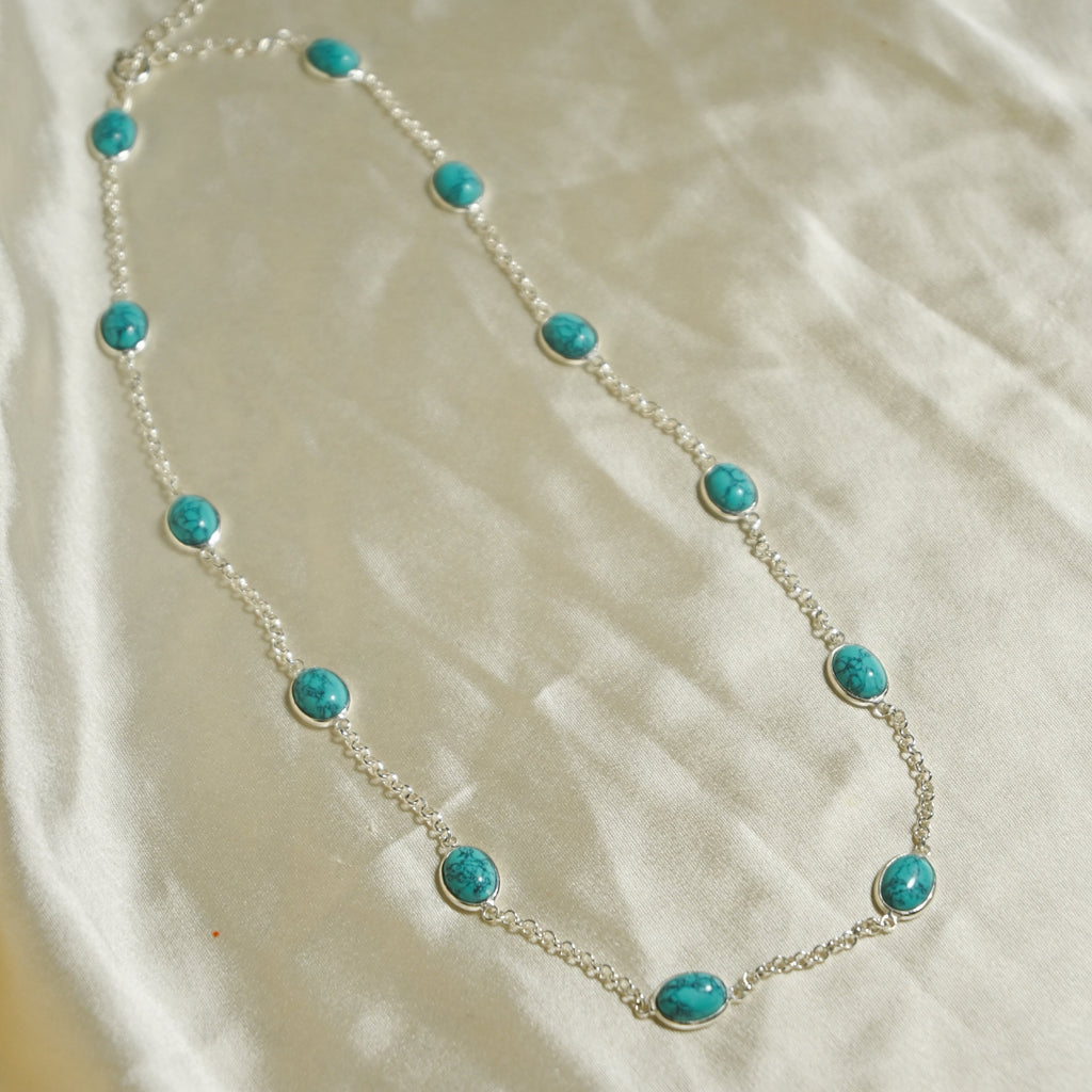 Necklace with turquoise beads on a beige fabric background