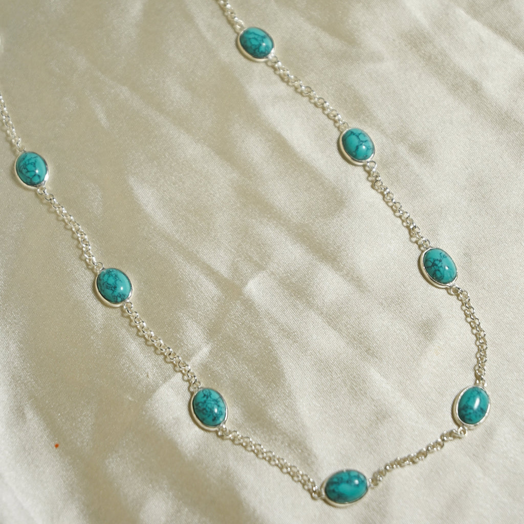 Necklace with turquoise beads on a beige fabric background