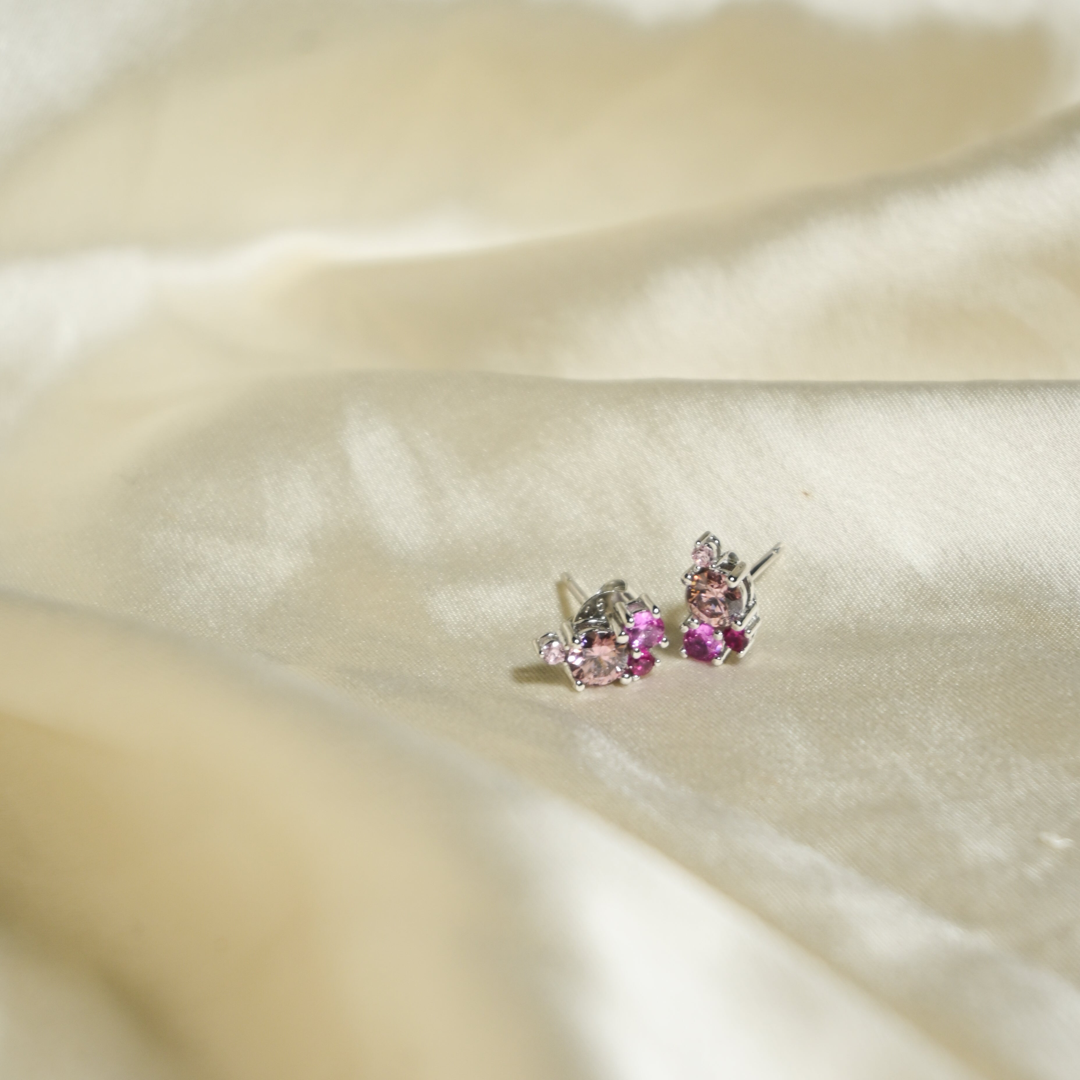 Pair of earrings with pink gemstones on a beige fabric background