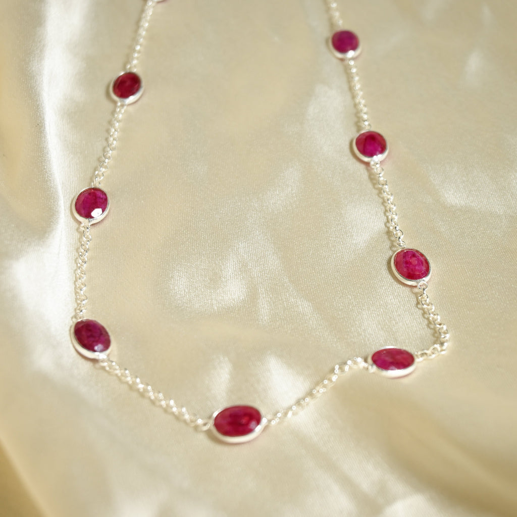 Necklace with red gemstones on a beige fabric background
