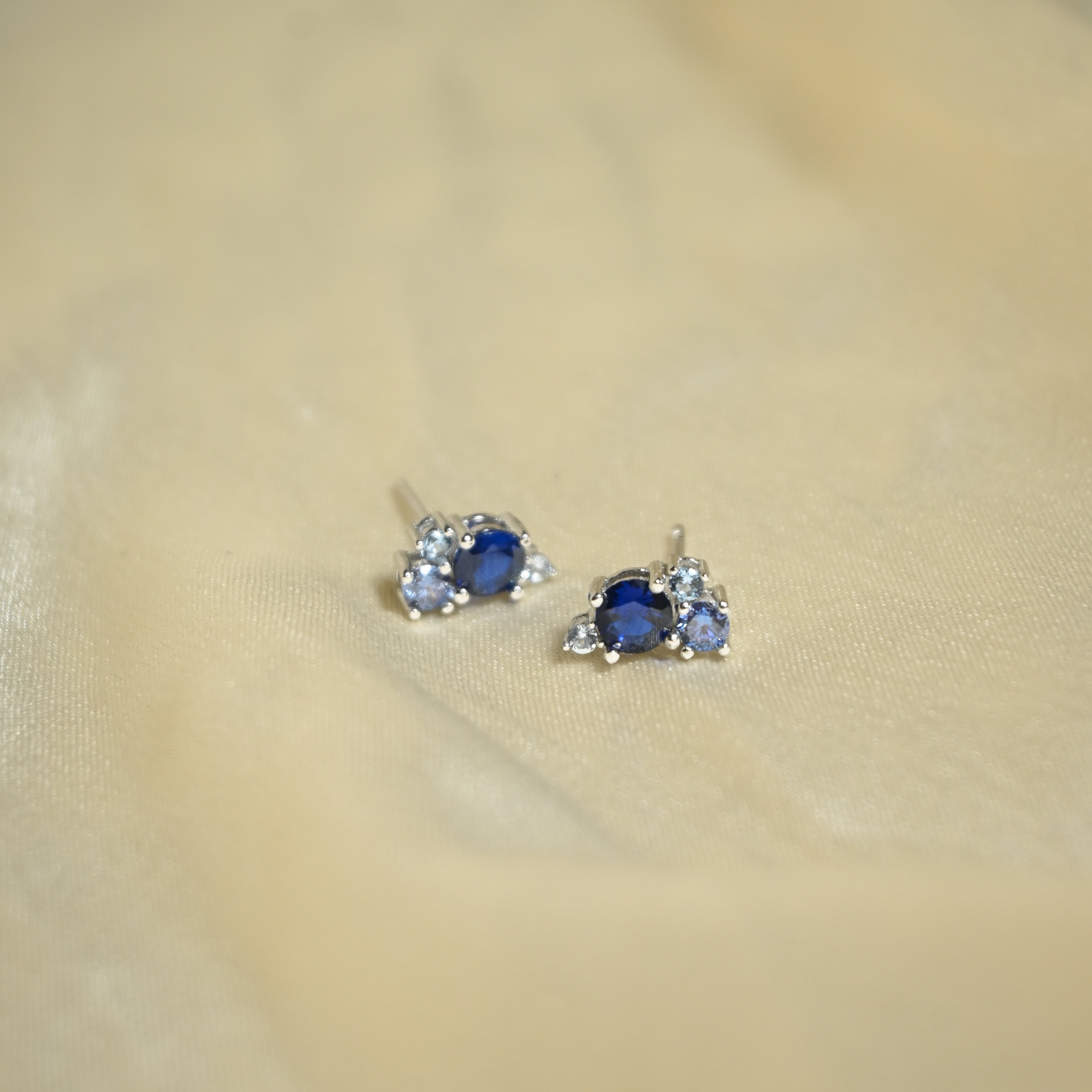 Pair of earrings with blue gemstones on a beige fabric background