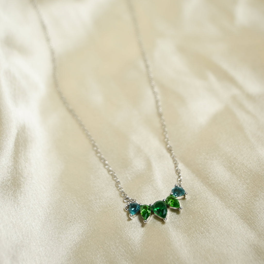 Necklace with green gemstones on a beige fabric background