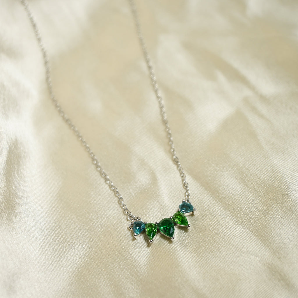 Necklace with green gemstones on a white fabric background