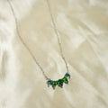 Necklace with green gemstones on a white fabric background