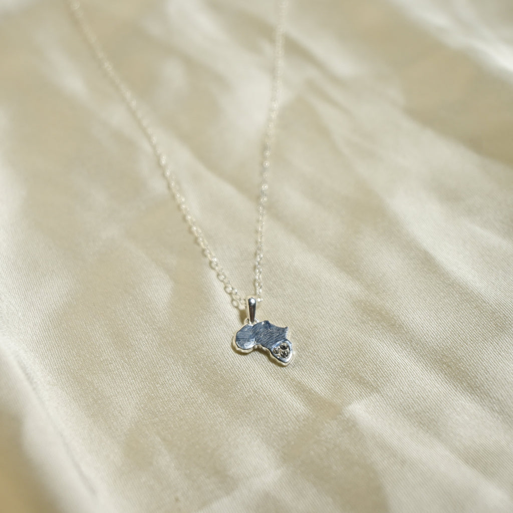 Small blue pendant on a chain against a beige fabric background