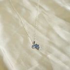 Small blue pendant on a chain against a beige fabric background