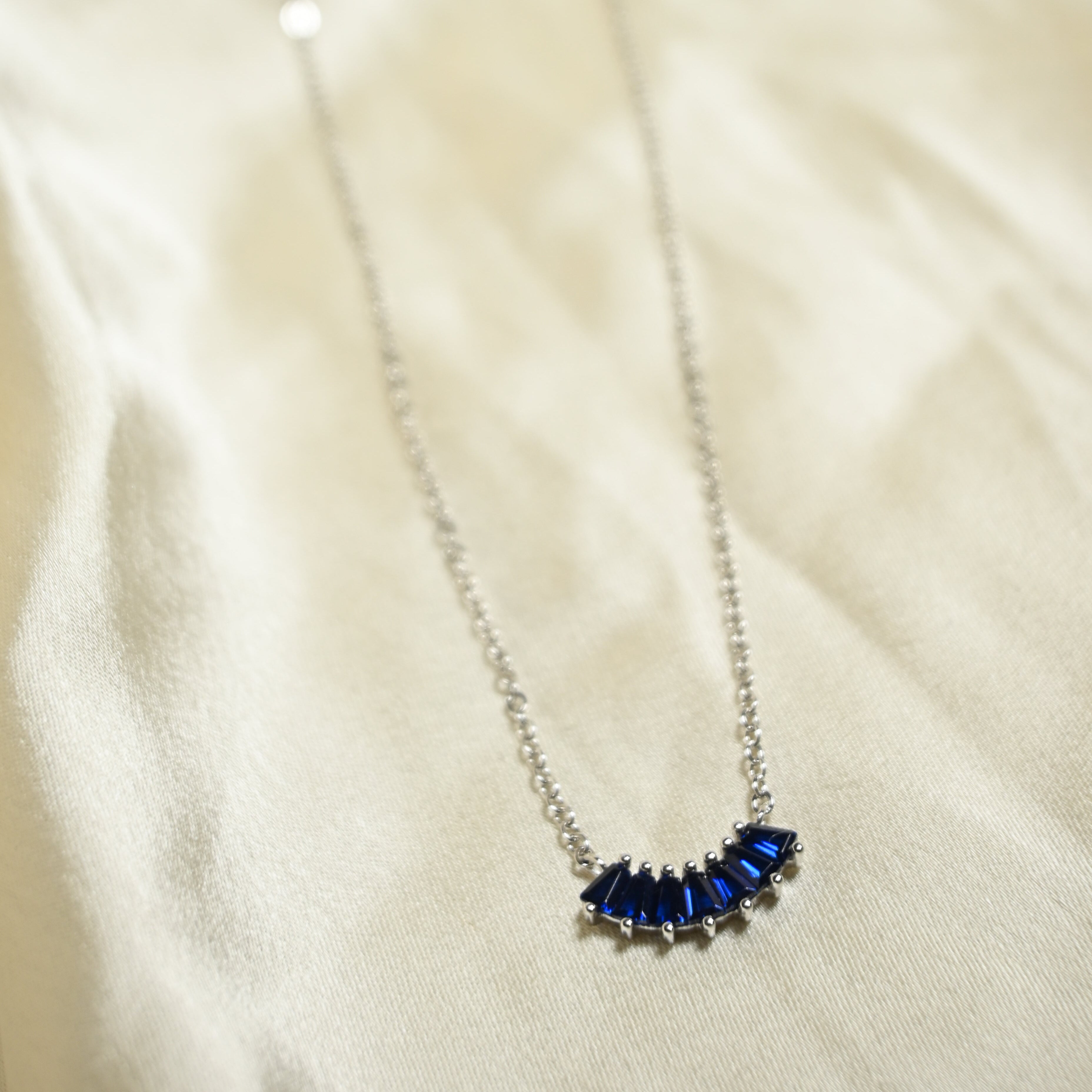 Necklace with blue gemstones on a beige fabric background