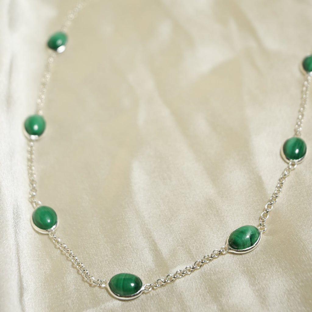 Necklace with green beads on a white fabric background
