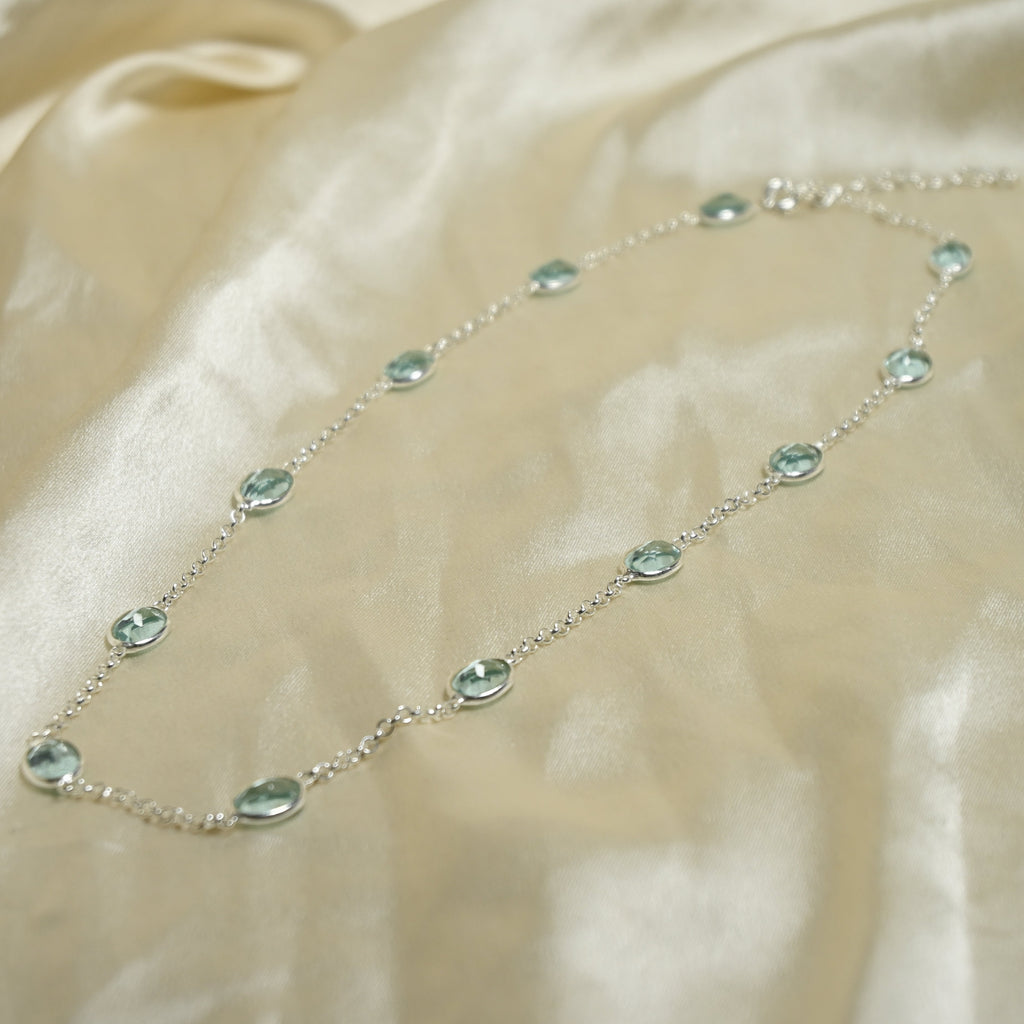 Necklace with green gemstones on a beige fabric background