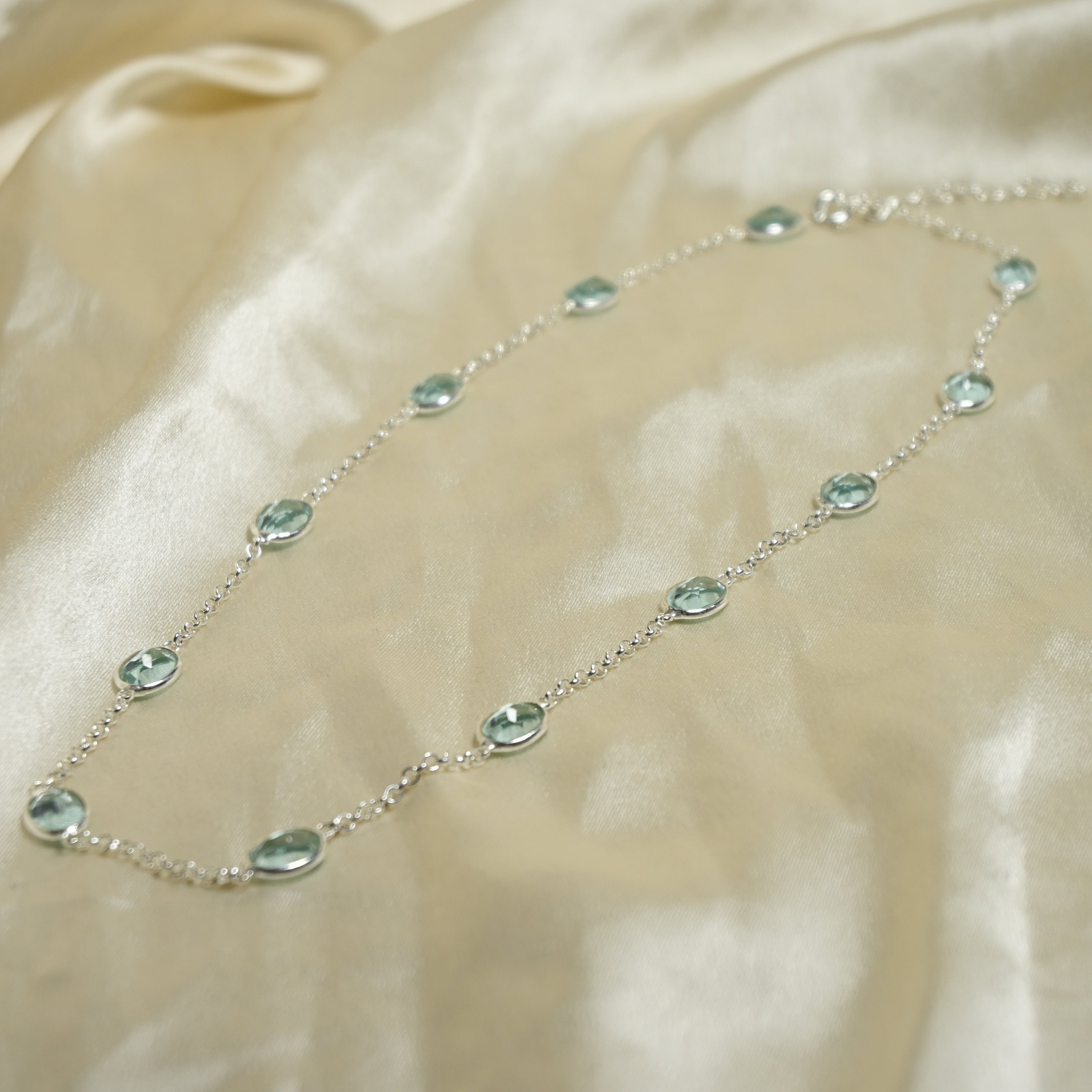 Necklace with green gemstones on a beige fabric background