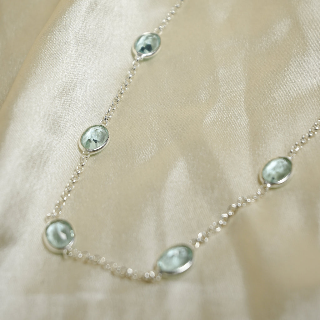 Necklace with green gemstones on a beige fabric background