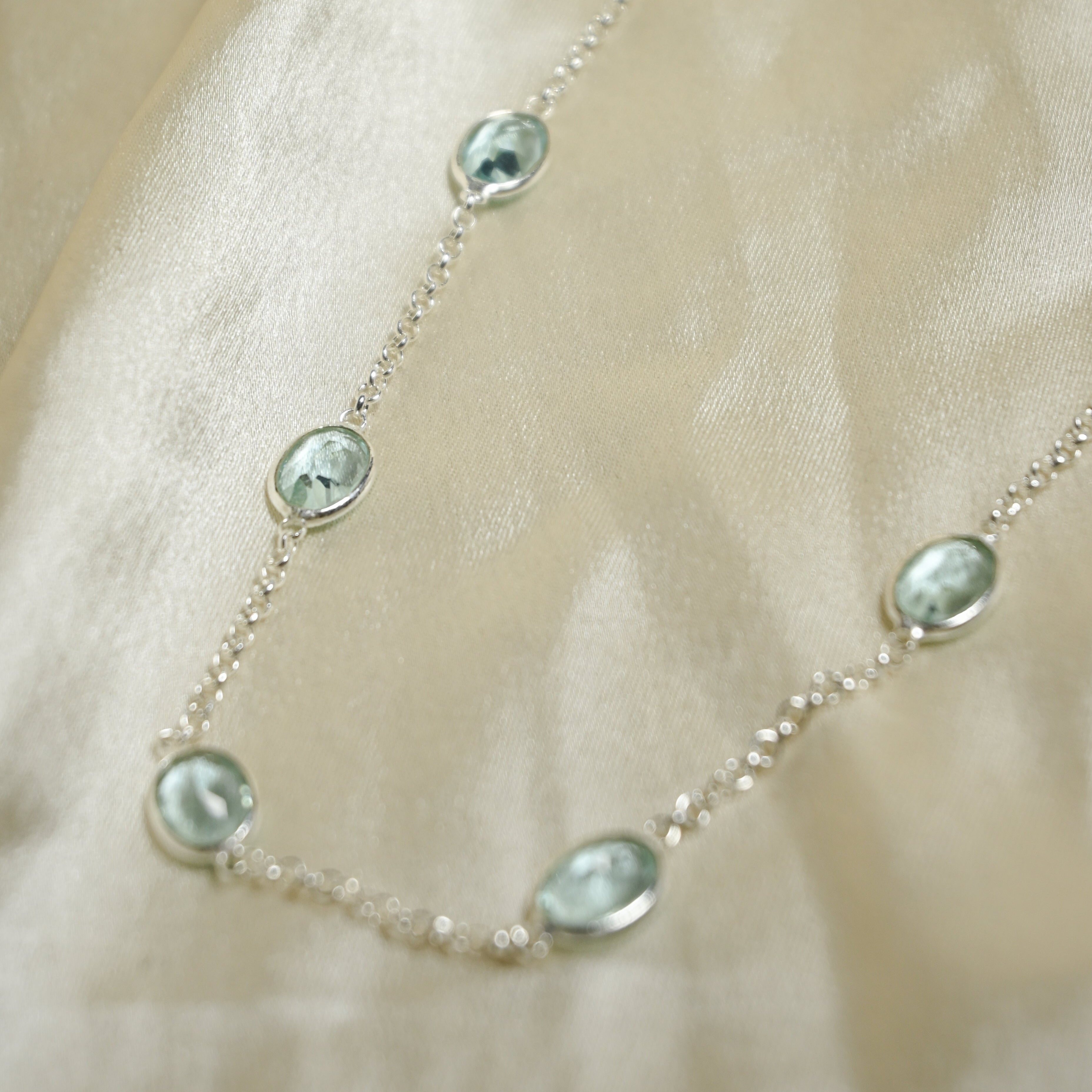 Necklace with green gemstones on a beige fabric background
