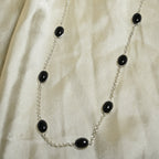 Necklace with black beads on a beige fabric background