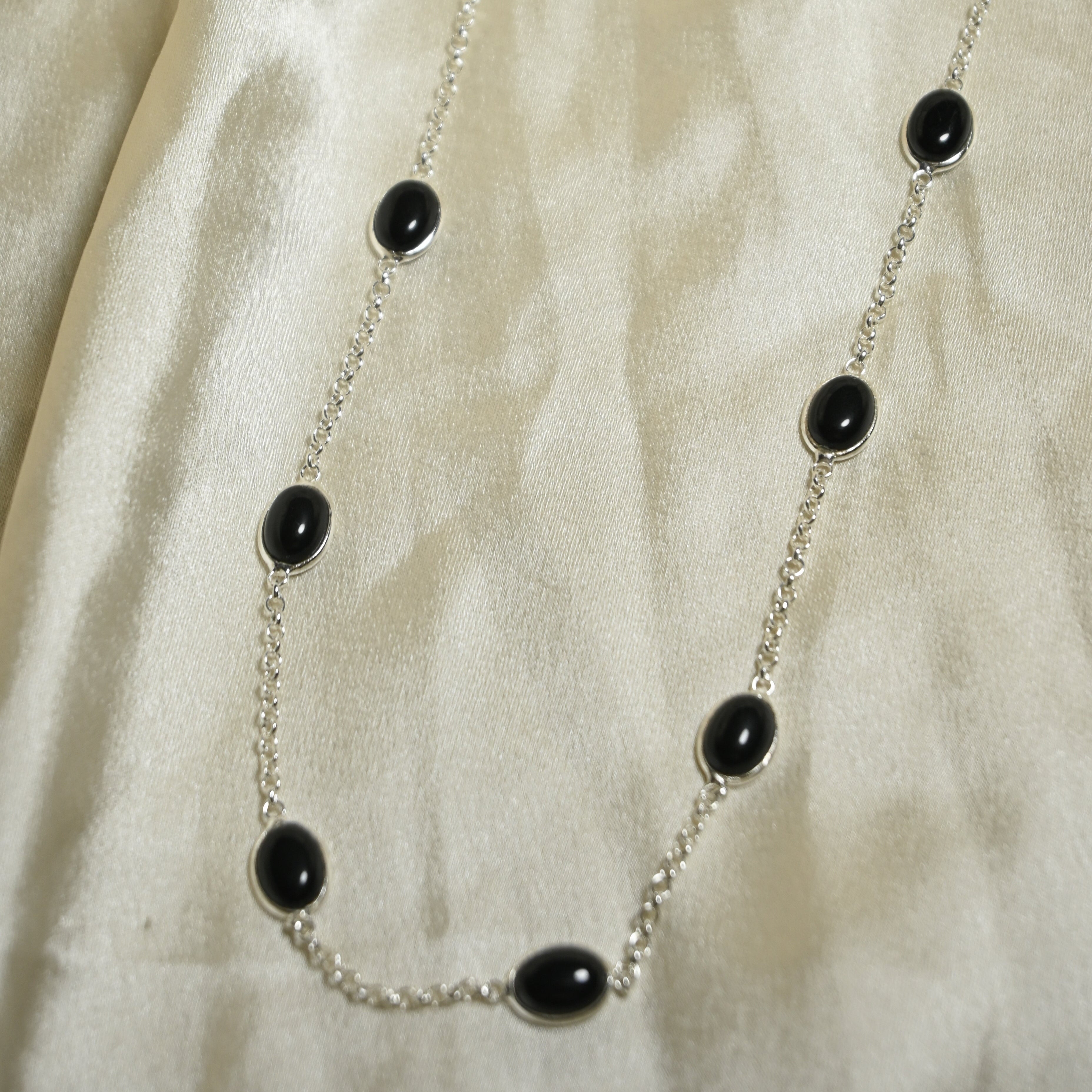 Necklace with black beads on a beige fabric background