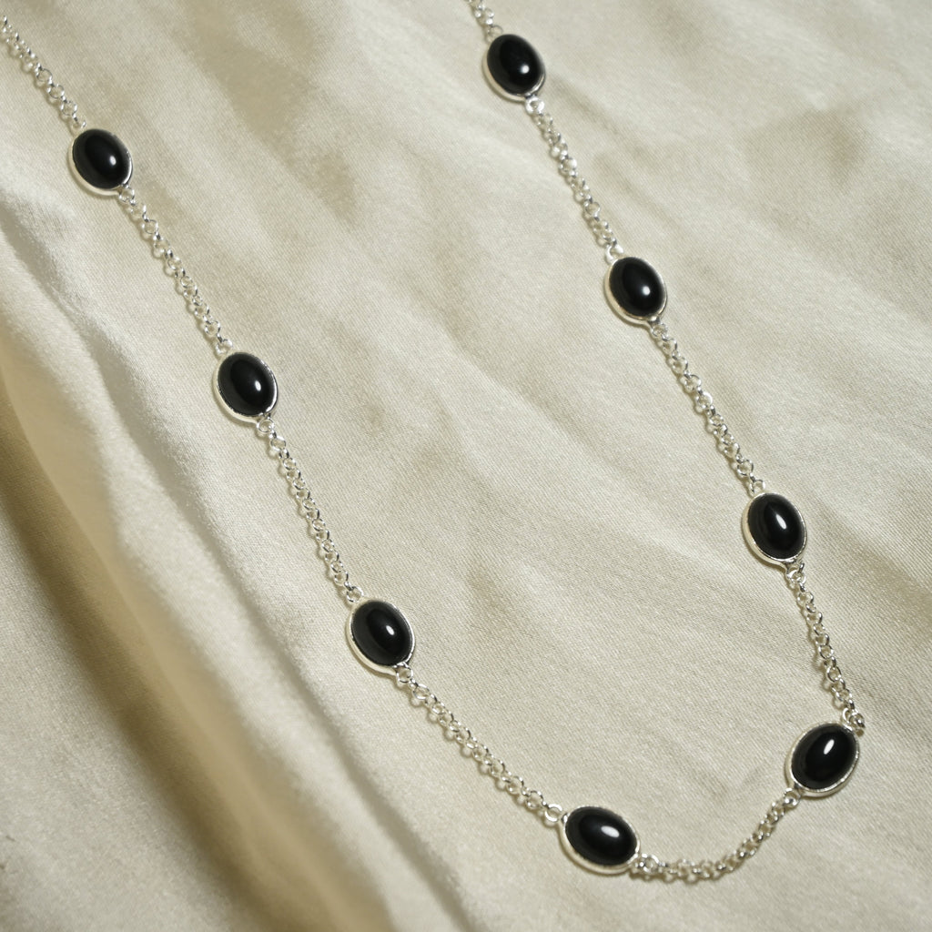 Necklace with black beads on a beige fabric background