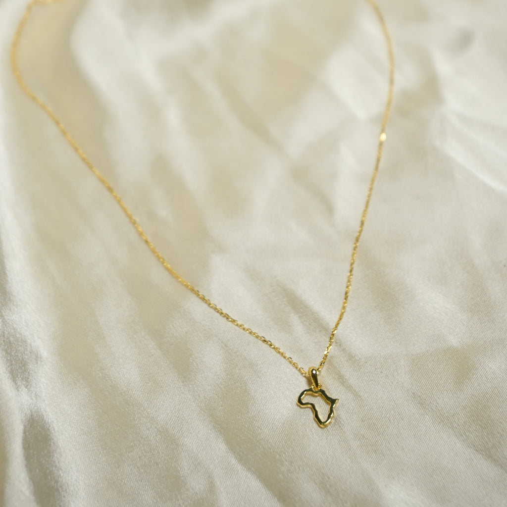 Gold necklace with a small pendant on a textured beige fabric background