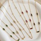 Gold necklaces with gemstone pendants on a white surface