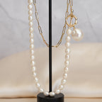 Pearl necklace and earrings on a black stand with a neutral background