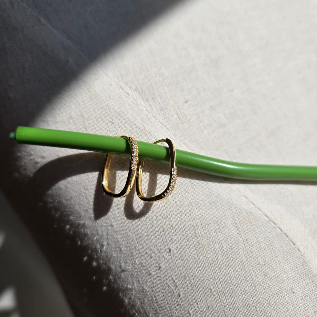 Two gold rings on a green stick against a textured surface