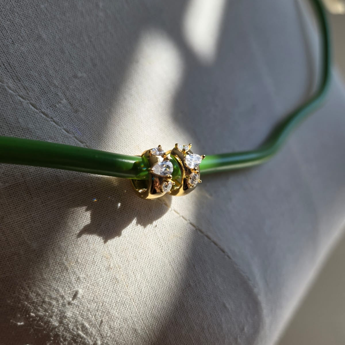Green necklace with a gold clasp on a textured surface