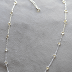 Silver necklace with small beads on a gray surface