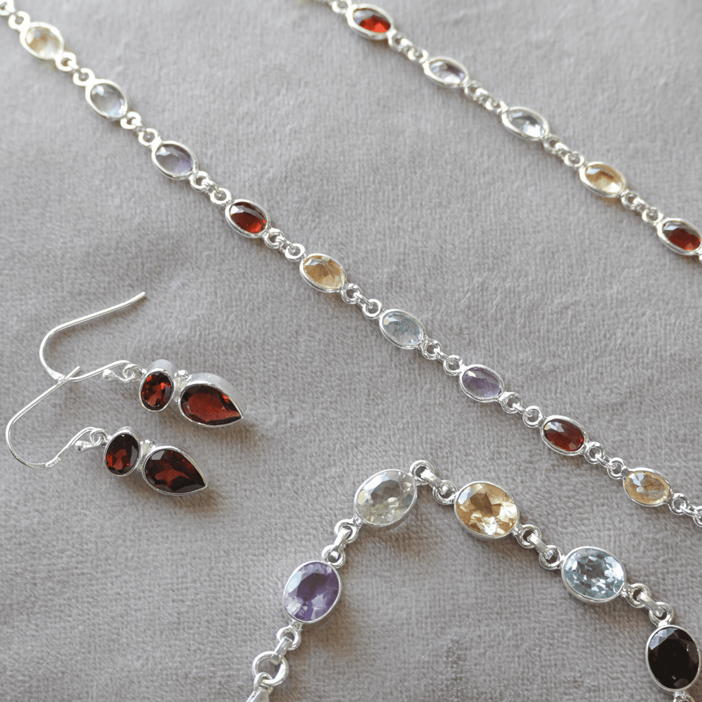 Silver jewelry set with gemstones on a gray surface