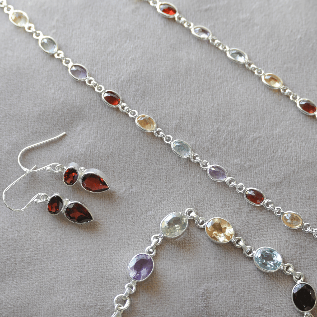 Silver jewelry set with gemstones on a gray surface