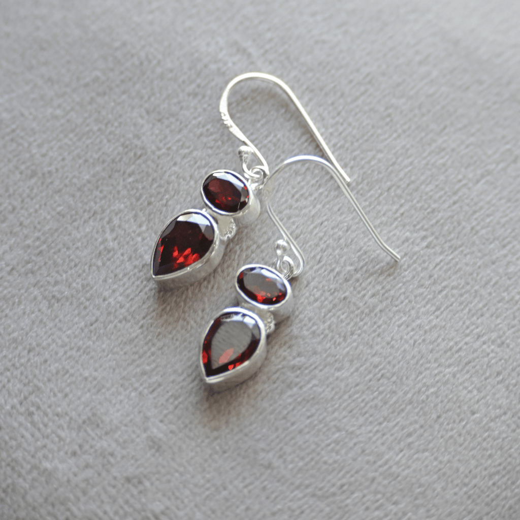 Silver earrings with red gemstones on a gray background