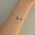 Silver bracelet with blue gemstones on a wrist against a neutral background