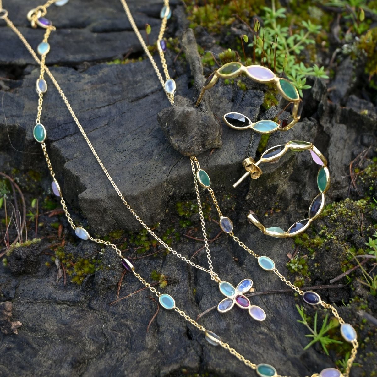 Jewelry set with necklaces and a bracelet on a stone surface