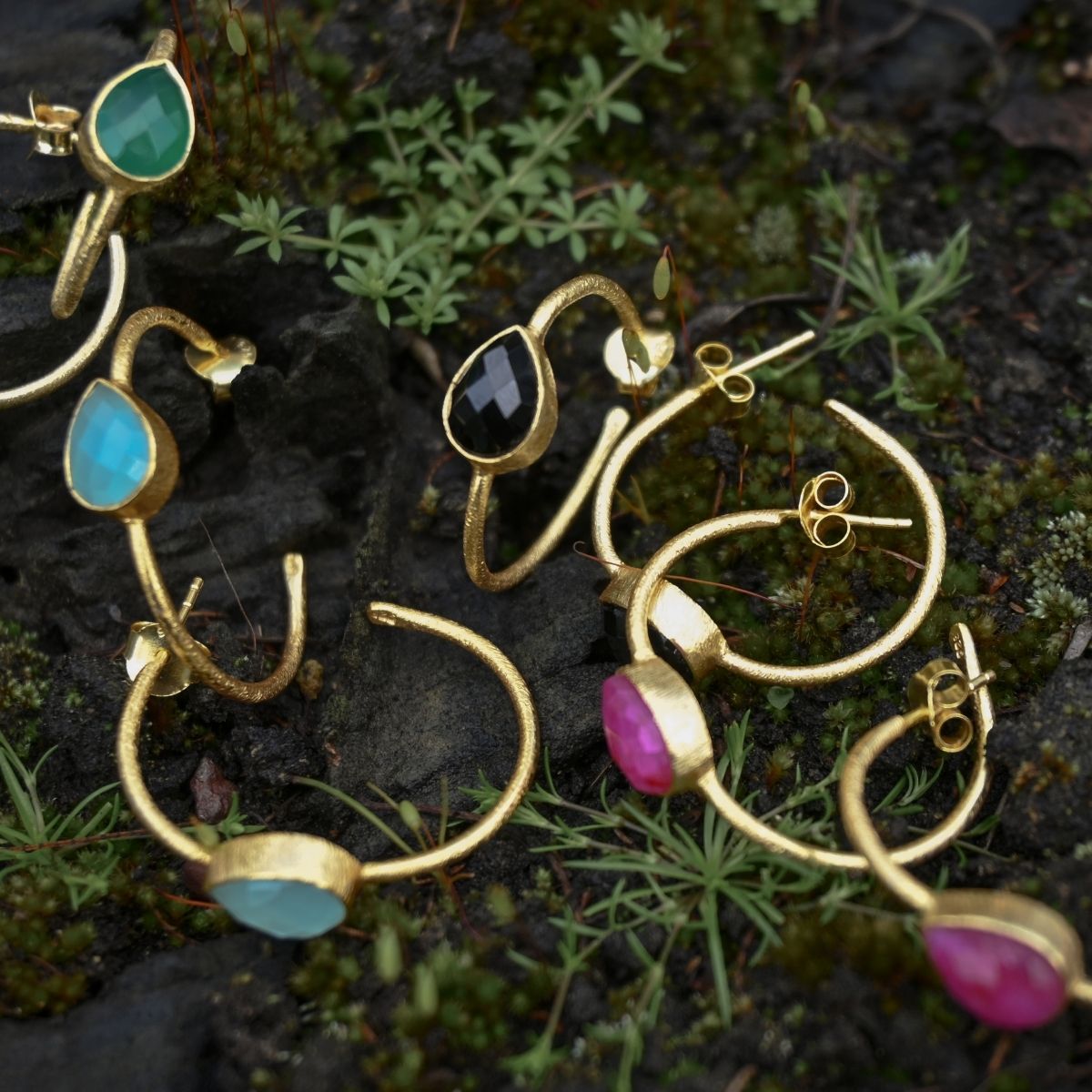 Gold earrings with gemstones on a natural background