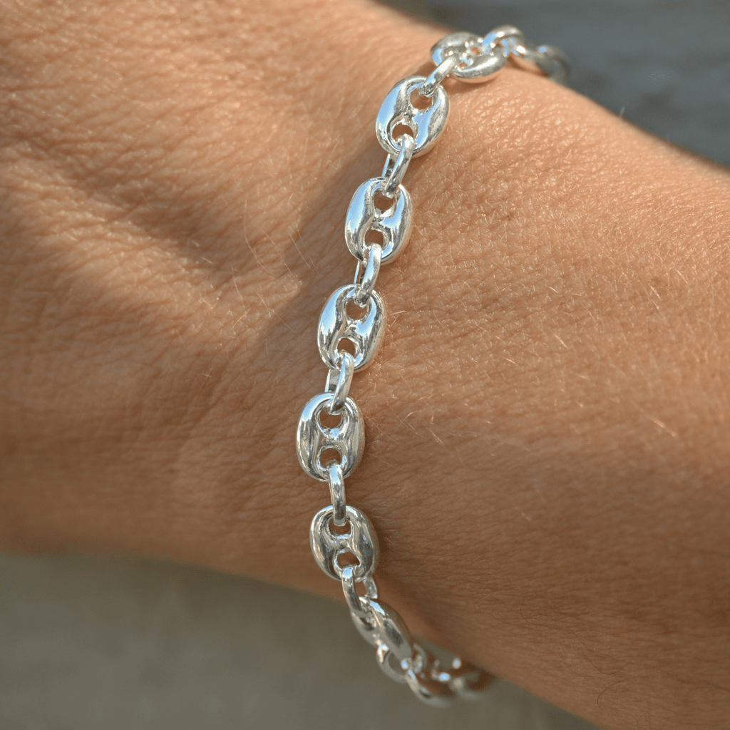 Silver chain bracelet on a wrist with a neutral background