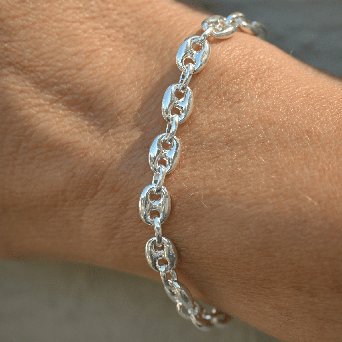 Silver chain bracelet on a wrist with a neutral background