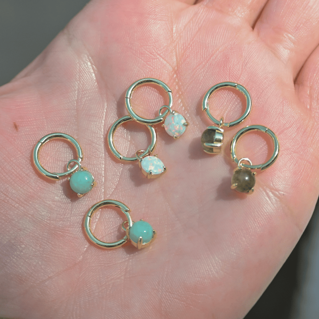 Gold hoop earrings with gemstones on a hand