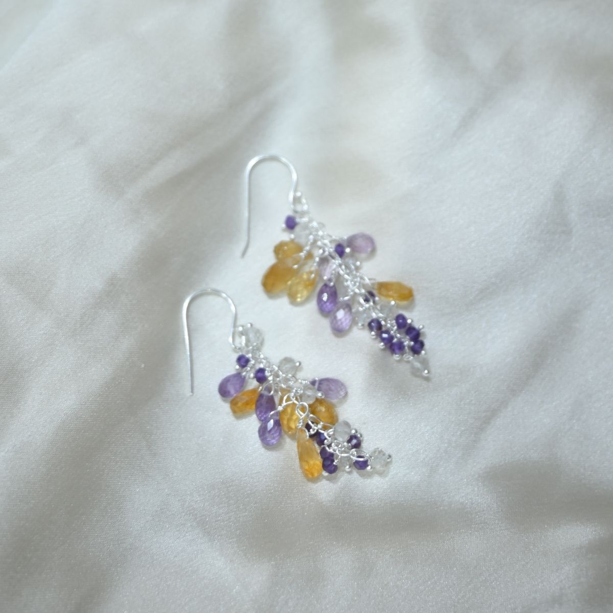 Beaded earrings with purple and yellow beads on a white fabric background