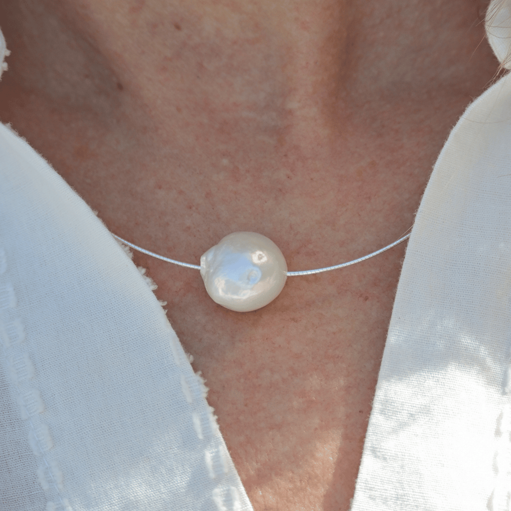 Pearl necklace on a person wearing a white shirt