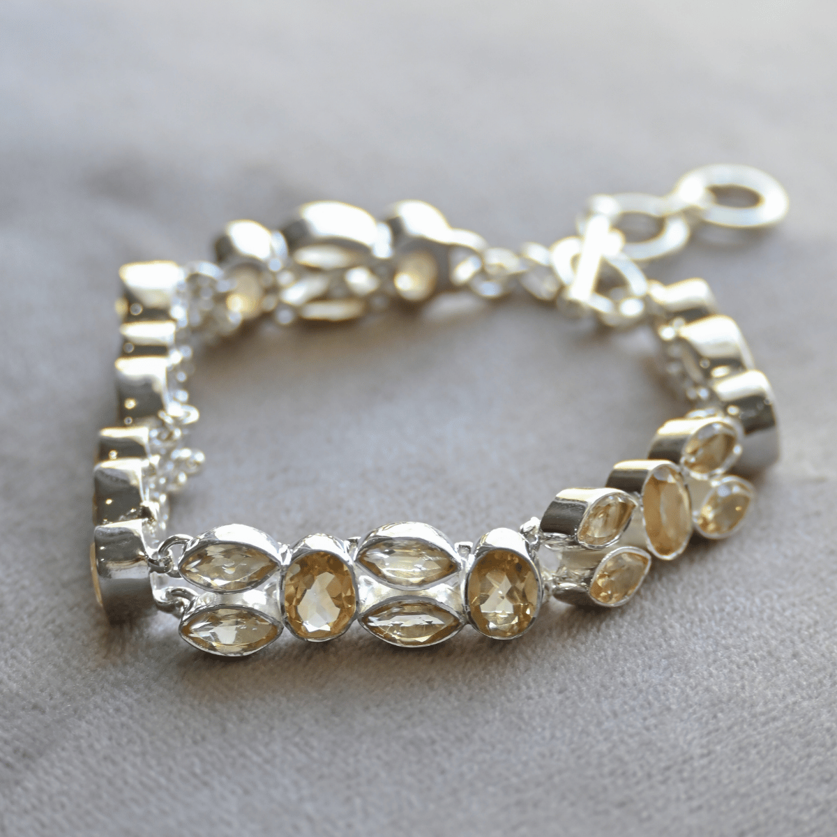 Silver bracelet with yellow gemstones on a light gray background